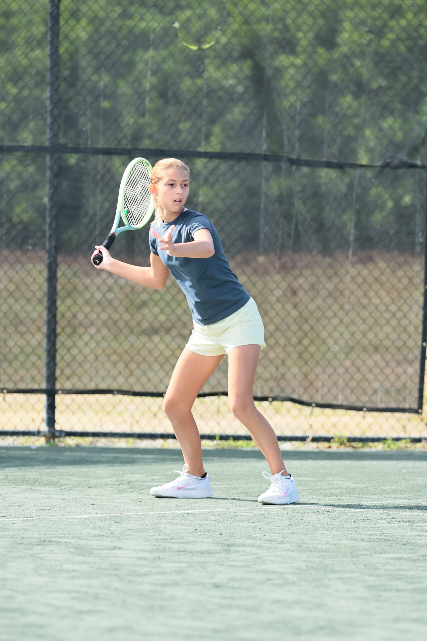 Young girl playing tennis on court